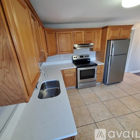A kitchen with wooden cabinets and a stainless steel refrigerator.
