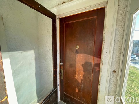 A brown door with a brass handle is in a room with white walls.