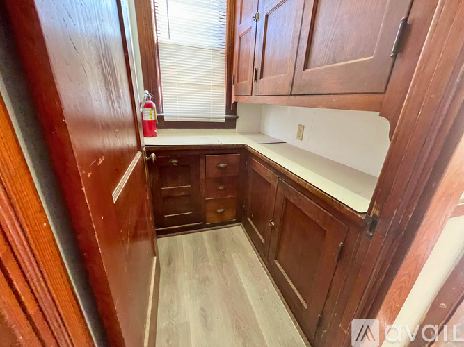A kitchen with wooden cabinets and a red fire extinguisher on the counter.