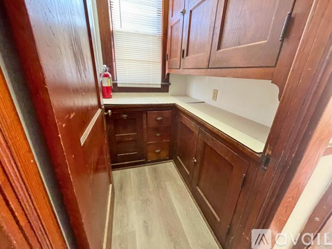 A kitchen with wooden cabinets and a red fire extinguisher on the counter.