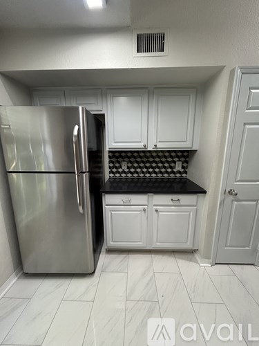 A kitchen with a stainless steel refrigerator and white cabinets.