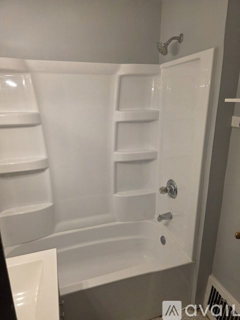 A white bathtub with a shower head and a faucet.