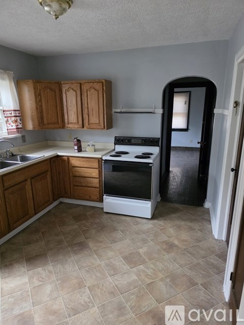 A kitchen with a stove top oven and wooden cabinets.