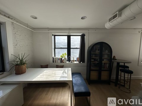 A room with a white table, a bench, a potted plant, and a bookshelf.