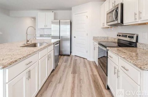 A kitchen with white cabinets and a granite countertop.