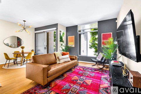 A living room with a brown couch and a red rug.