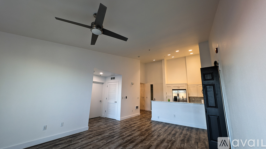 A spacious room with a ceiling fan and wooden flooring.