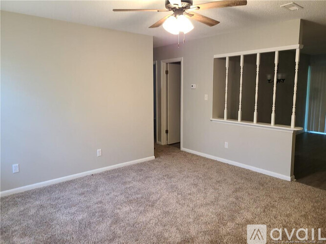 A room with a ceiling fan and carpeted floor.