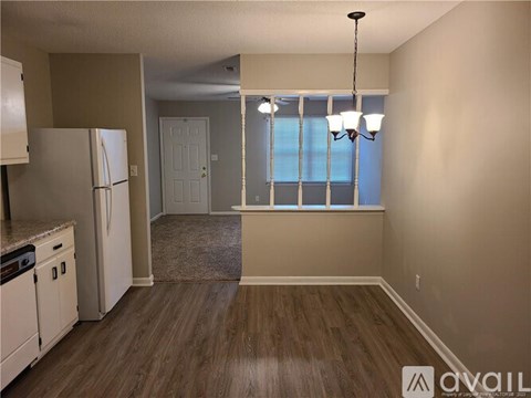A kitchen with white appliances and a wooden floor.