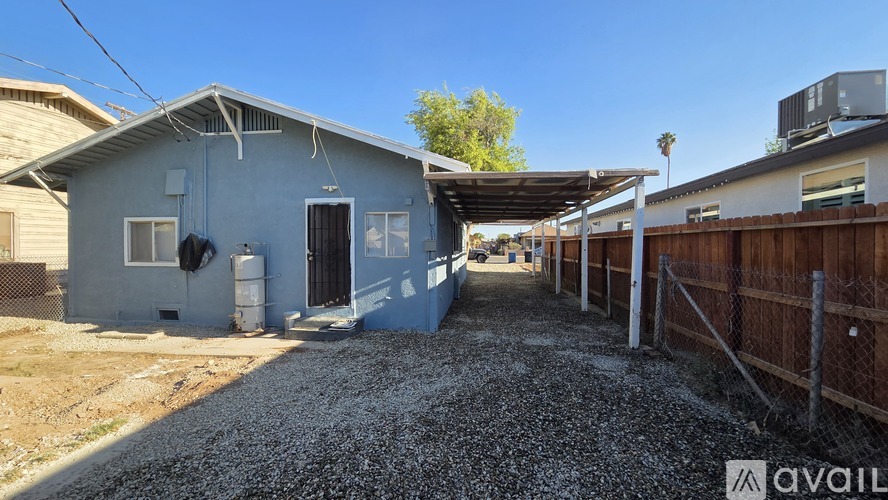 A gravel driveway leads to a small house with a covered patio.