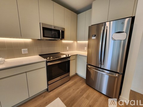 A modern kitchen with a stainless steel refrigerator and microwave above the stove.