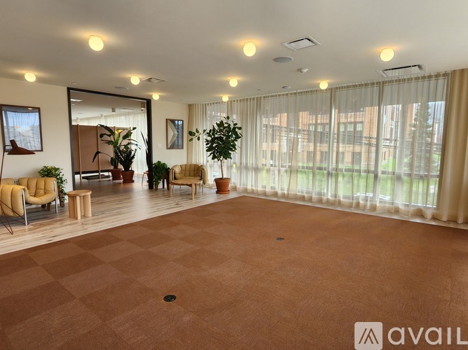 A spacious room with a checkered floor and a large window with curtains.