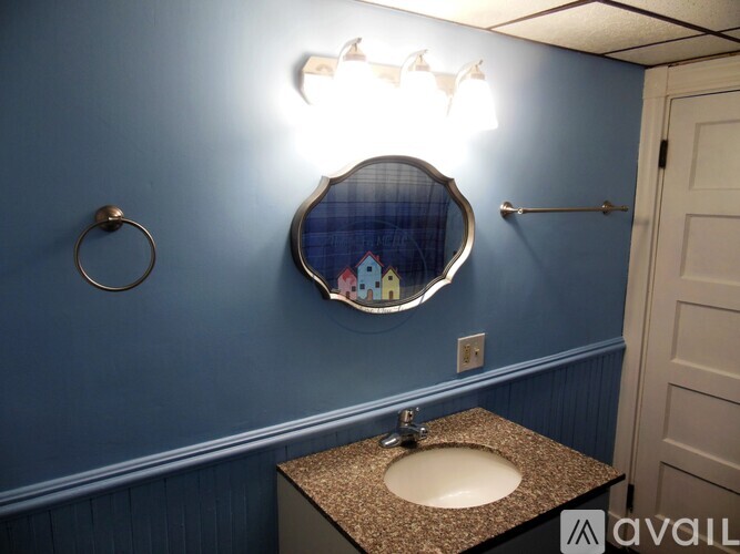 A bathroom with blue walls and a round mirror above a sink.