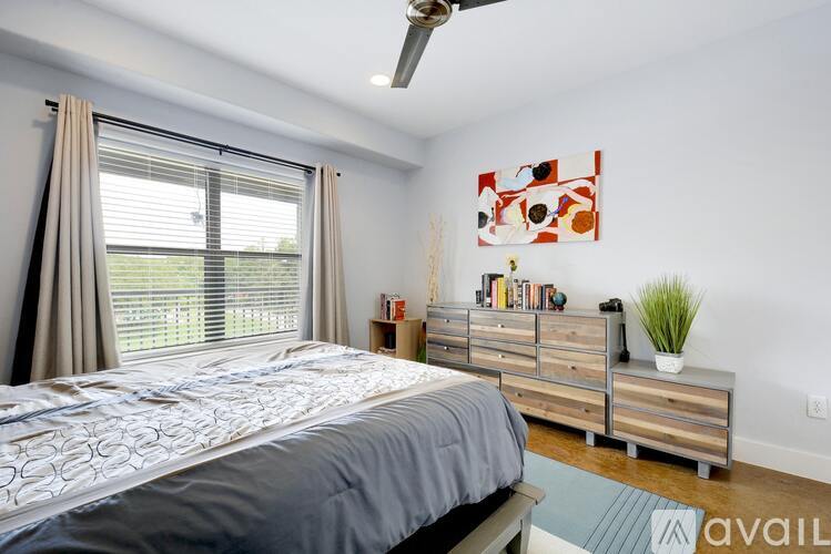 A bedroom with a bed, a dresser, and a ceiling fan.