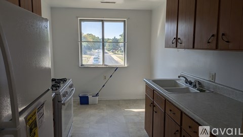 A kitchen with a white fridge and a window overlooking a street.