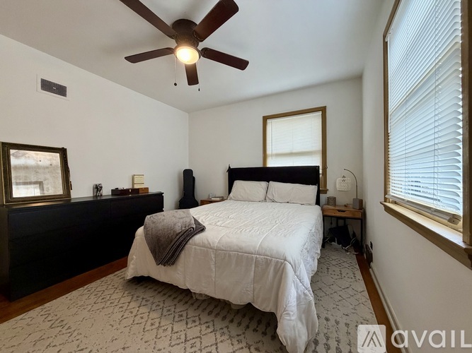 A bedroom with a bed, a ceiling fan, and a window with blinds.