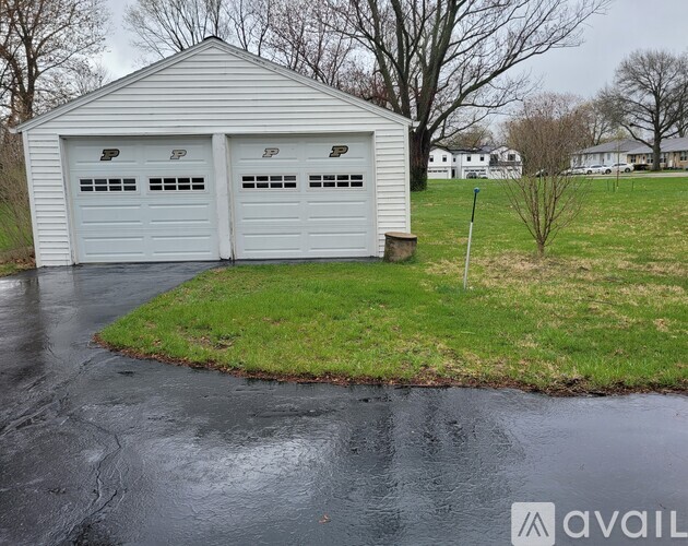 A white garage with three doors is situated in a grassy area.