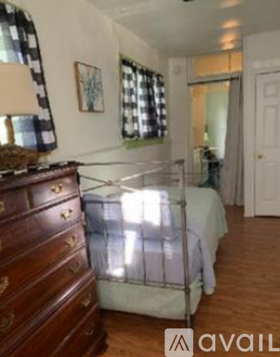 A bedroom with a bed, dresser and window.
