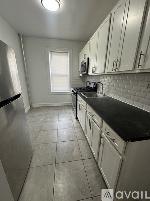 A kitchen with white cabinets and a black countertop.