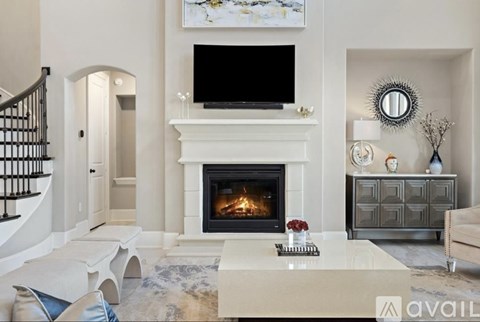 A living room with a fireplace and a television mounted above it.