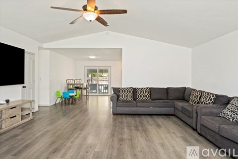 A living room with a grey couch and a ceiling fan.