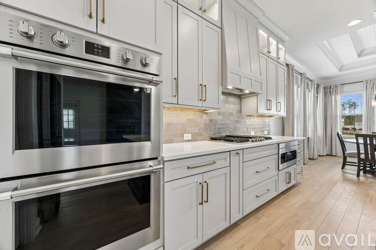 A modern kitchen with a stainless steel oven and white cabinets.