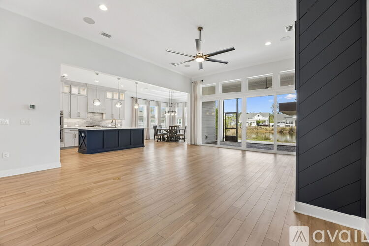 A spacious living room with a ceiling fan and hardwood floors.