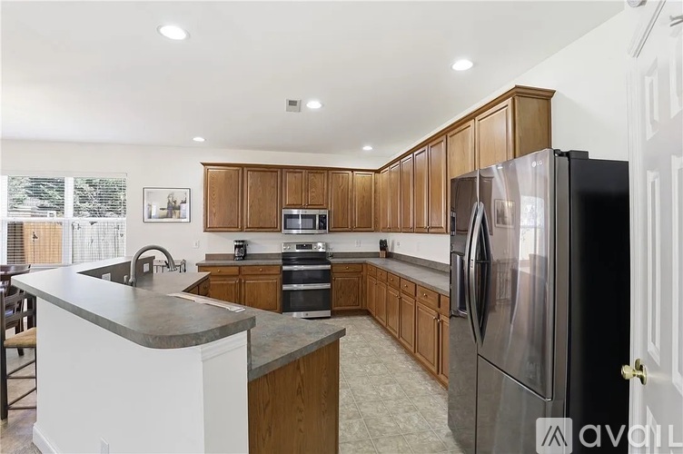 A kitchen with wooden cabinets and a black refrigerator.