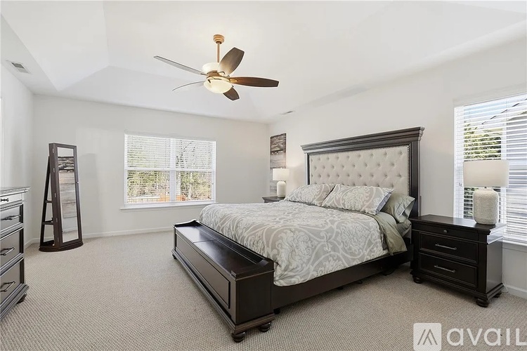 A bedroom with a large bed and a ceiling fan.