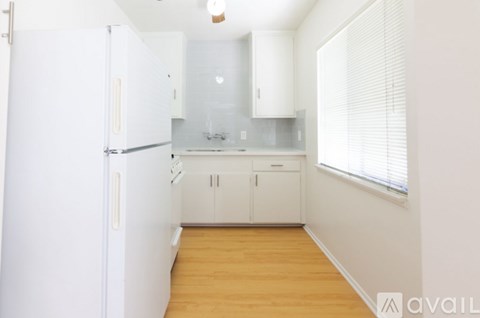 A kitchen with white cabinets and a white refrigerator.