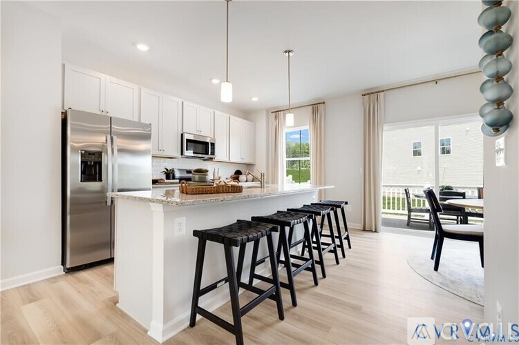 A kitchen with white cabinets and a white island with black bar stools.