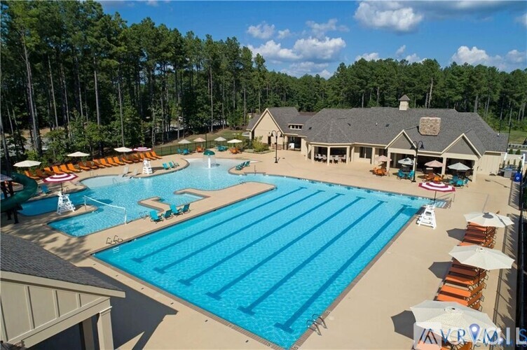 A large outdoor swimming pool with sun loungers and a building in the background.