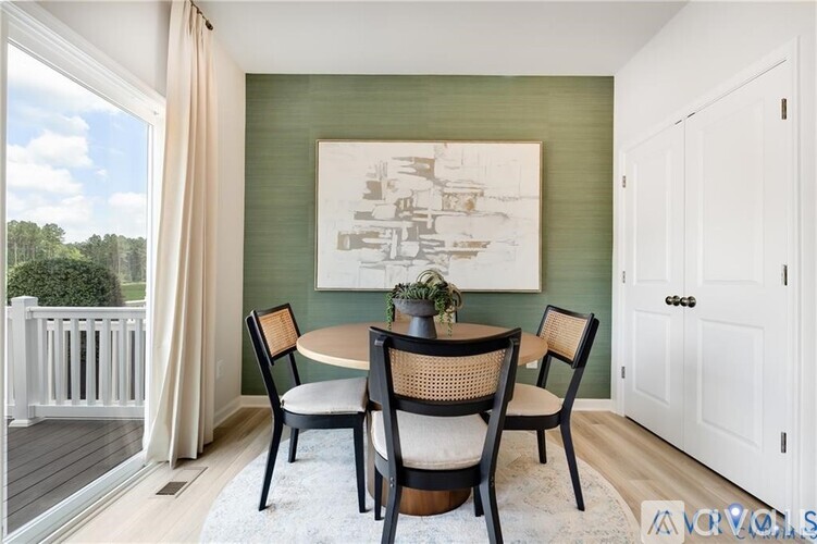 A dining room with a table set for two and a painting on the wall.
