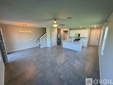 A spacious living room with a kitchen in the background.