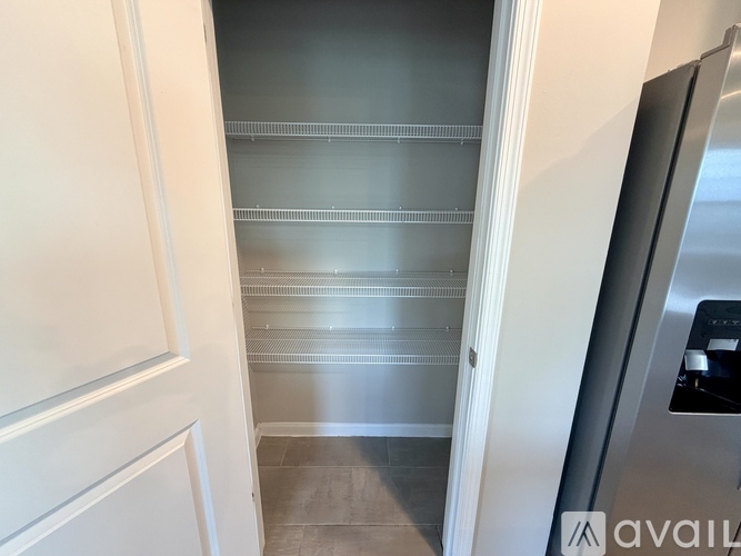 A kitchen with a refrigerator on the right and empty shelves.