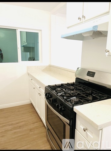 A kitchen with a black stove top oven and white cabinets.