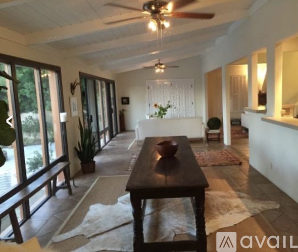 A living room with a wooden table and a ceiling fan.