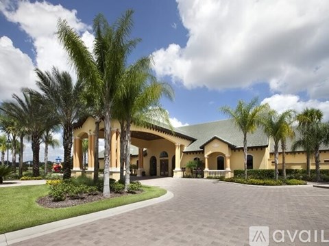 A large, luxurious house with a driveway and palm trees in front.