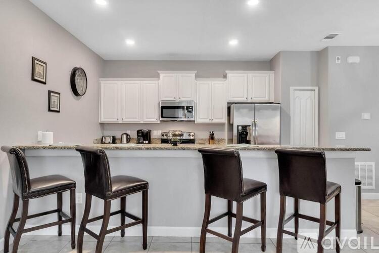 A kitchen with white cabinets and a marble countertop.