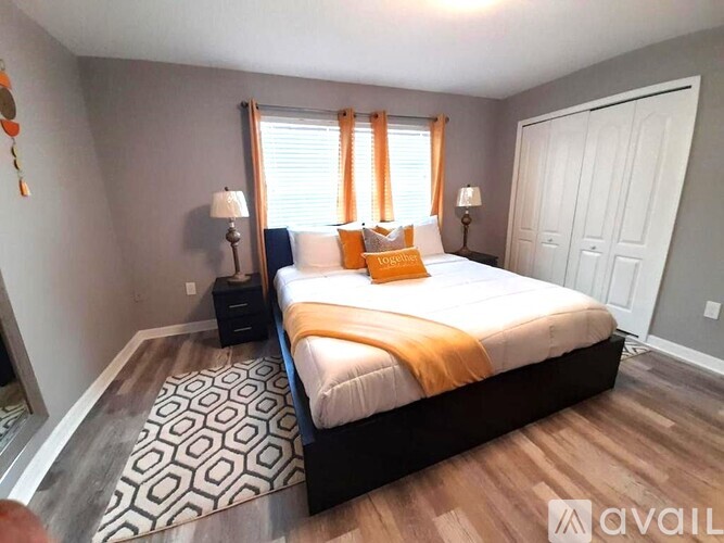 A bedroom with a large bed and a patterned rug.