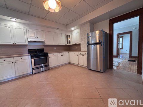 A kitchen with white cabinets and a stainless steel refrigerator.