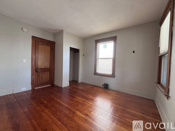 A room with wooden floors and a window with blinds.