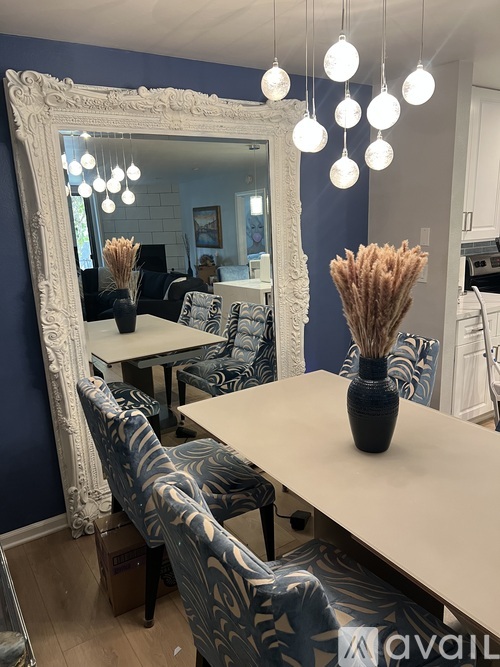 A dining room with a large mirror and a vase on the table.