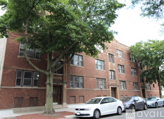 A white car is parked in front of a brick building.