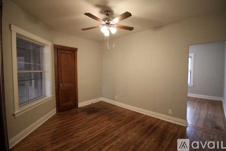 A room with a ceiling fan and wooden floors.