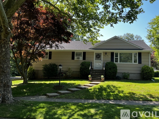A house with a front yard and a tree in front of it.