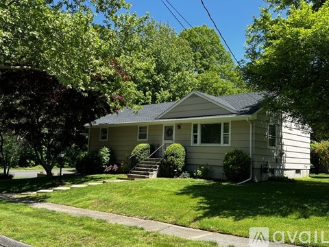 A house with a green lawn and trees in the background.