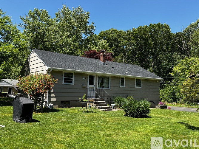 A house with a grey roof and a tree in front of it.