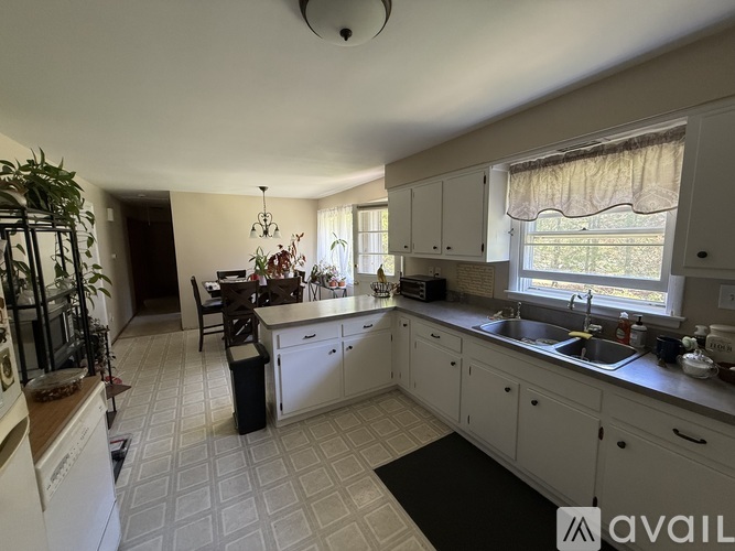 A kitchen with white cabinets and a black mat on the floor.