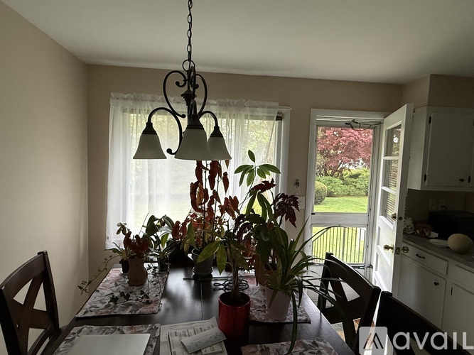 A dining room with a table set for four and a chandelier hanging from the ceiling.